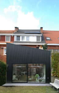 Friday office bouwde een uitbouw voor een bestaande woning: met gevel die bovenaan een schuin aflopende gevel. De gevel is uitgevoerd in donker gekleurd hout.