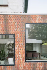 oude veranda wordt volwaardig volume naast half-open bebouwing- Architectuurbureau Friday Office For Architecture. Verspringende raamvlakken in een bakstenen gevel met verticaal metselverband.