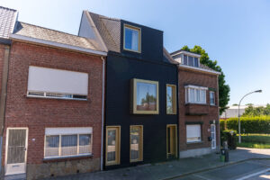 HOUSE SKIN door Friday office for architecture: facelift van rijwoning met nieuwe dakconstructie door monoliete gevel- en dakafwerking in donkerkleurige leien en goudkleurige raamkaders.
