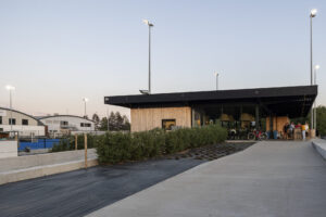 Nieuwbouw hockeyclub voor Royal victory Hockey in Edegem door Friday Office for architecture. Een nieuwbouw clublokaal met houten gevels en een overkragend zwart dak dat dienst doet als luifel.