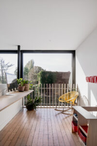 De uitbouw voor House Kwartet is zo simpel als het complex is. Twee schuiframen zijn boven elkaar geplaatst, that’s it. Het schuifraam op de eerste verdieping kan de bureau volledig openen. Ter hoogte van het vaste glaspaneel is er een vide die de verbinding vormt tussen keuken/eetruimte, bureau en slaapkamer. Alles baadt in het licht. De badkamer werd verplaatst en kreeg een opvallende en frivole afwerking.