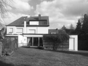 Een nieuwe uitbouw voor de bewoners! De oorspronkelijke jaren '70 uitbouw is volledig vervangen en dient nu als extra binnenruimte die perfect geïntegreerd is. Alle belangrijke leefruimtes hebben nu direct contact met de tuin. Deze foto geeft de oorspronkelijke toestand weer.