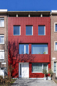 Een rijwoning wordt omgetoverd tot een lichtrijke gezinswoning. De voorgevel wordt geïsoleerd en afgewerkt met rode keramische tegels. Refererend naar de bestaande gevelstructuur is er gewerkt met verschillende voegkleuren en patronen.