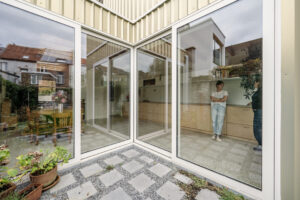 Renovatie van een gezinswoning door friday office for architecture. Achtergevel met licht-goude aluminiumbekleding. Een hoekschuifraam verbindt de leefruimte met de tuin.