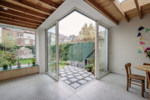 Renovatie van een gezinswoning door friday office for architecture. Achtergevel met licht-goude aluminiumbekleding. Een hoekschuifraam verbindt de leefruimte met de tuin.