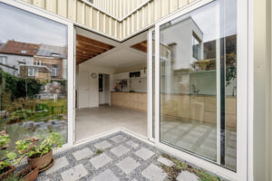 Renovatie van een gezinswoning door friday office for architecture. Achtergevel met licht-goude aluminiumbekleding. Een hoekschuifraam verbindt de leefruimte met de tuin.