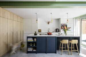 renovatie van een gezinswoning door Friday office for architecture in Mortsel. Dubbelhoge leefruimte met ruime ramen die uitzicht bieden op de tuin. De bovenverdieping wordt gedragen. door karakteristieke groene liggers.
