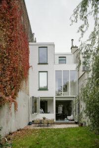 Verbouwing van een gezinswoning in Berchem door friday office for architecture. Op deze foto is de achtergevel te zien. De achtergevel werd voorzien van een grote vouwdeur en een ruim vouwraam waardoor interieur en exterieur in connectie komen met elkaar.