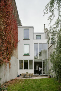 Verbouwing van een gezinswoning in Berchem door friday office for architecture. Op deze foto is de achtergevel te zien. De achtergevel werd voorzien van een grote vouwdeur en een ruim vouwraam waardoor interieur en exterieur in connectie komen met elkaar.