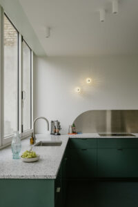 Verbouwing van een gezinswoning in Berchem door friday office for architecture. In de woning werd een nieuwe keuken voorzien met donkergroen maatwerk. De keuken is voorzien van een groot vouwraam- en deur waardoor de keuken rechtstreeks in contact komt met de tuin.