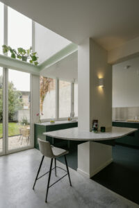 Verbouwing van een gezinswoning in Berchem door friday office for architecture. In de woning werd een nieuwe keuken voorzien met donkergroen maatwerk. De keuken is voorzien van een groot vouwraam- en deur waardoor de keuken rechtstreeks in contact komt met de tuin.