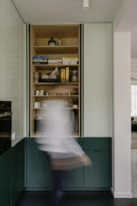 Verbouwing van een gezinswoning in Berchem door friday office for architecture. In de woning werd een nieuwe keuken voorzien met donkergroen maatwerk. De keuken is voorzien van een groot vouwraam- en deur waardoor de keuken rechtstreeks in contact komt met de tuin.